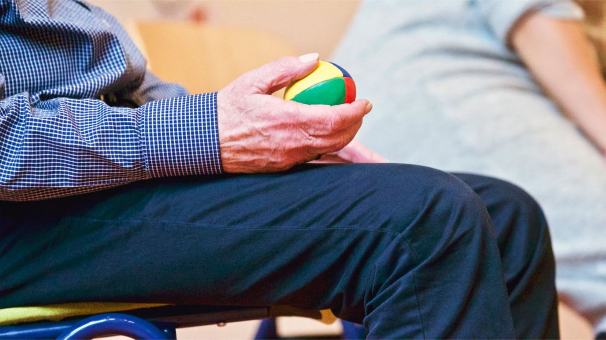 Objawy choroby Parkinsona - dłoń seniora podczas ćwiczeń chwytu w rehabilitacji neurologicznej